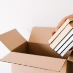 本を箱に入れて手放す準備をする人の手元