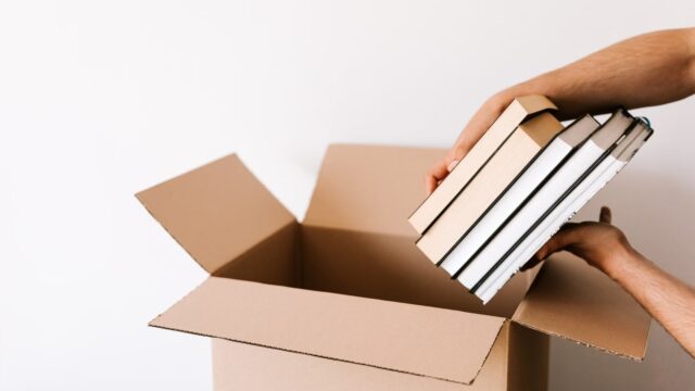 本を箱に入れて手放す準備をする人の手元