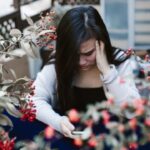 スマートフォンを見て不安そうに頭を抱える人